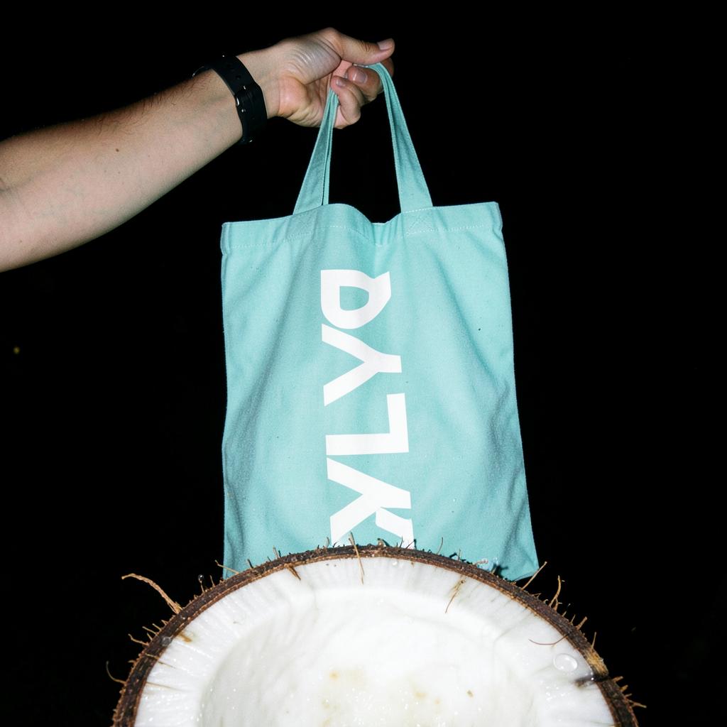 Aqua ZYLA tote bag held above a giant split coconut